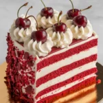 Cherry chip cake slice topped with whipped frosting and fresh cherries.