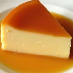 A creamy slice of Venezuelan quesillo topped with caramel, served on a white plate with a drizzle of caramel sauce.