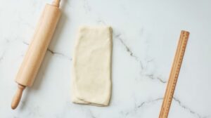 Rolled dough with a rolling pin and ruler, preparing for a Gipfeli recipe.
