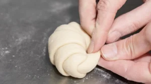 Rolling Gipfeli dough into a crescent shape with hands.